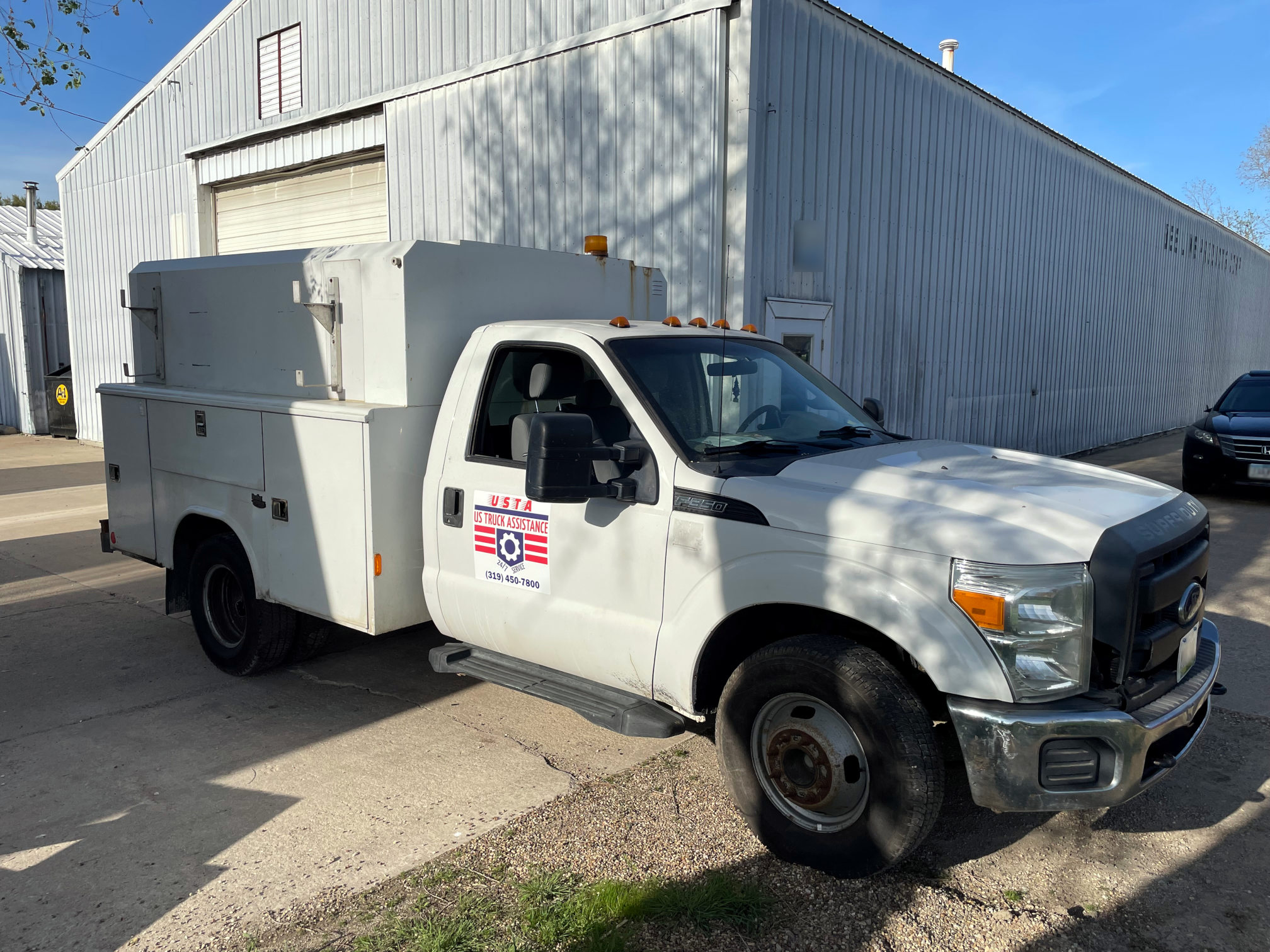 White work truck with the USTA decal on the door sitting in front of the shop.